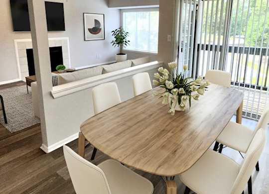 A dining room with a wooden table and white chairs.