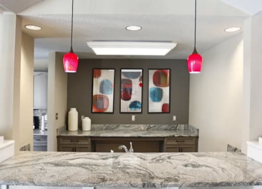 A kitchen with a marble countertop and black chairs.