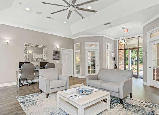 A living room with a white ceiling fan and grey couches.