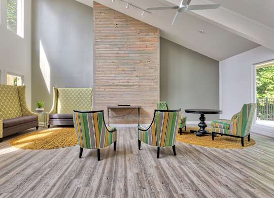 A living room with a brick wall and striped chairs.