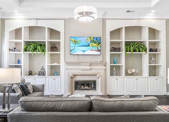 A living room with a grey couch and a fireplace.