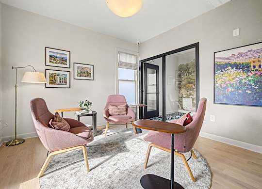 A living room with a grey rug and pink chairs.