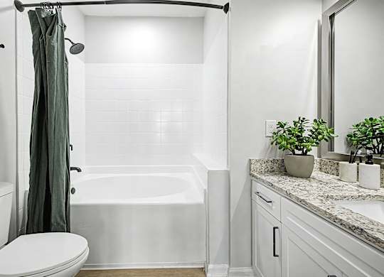 A white bathroom with a green shower curtain.
