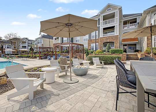 A patio with a table, chairs and an umbrella.