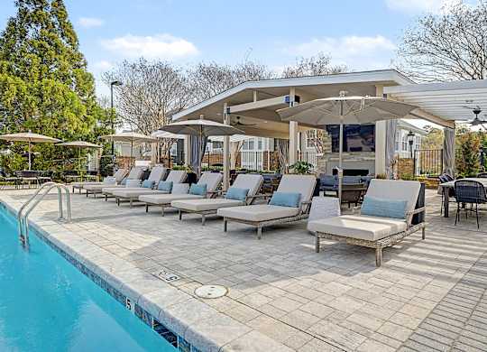 A poolside area with lounge chairs and a covered seating area.