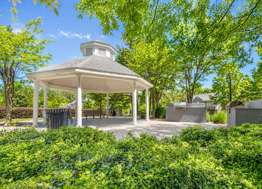 A gazebo is surrounded by green bushes.