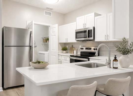 A modern kitchen with a white countertop and stainless steel appliances.