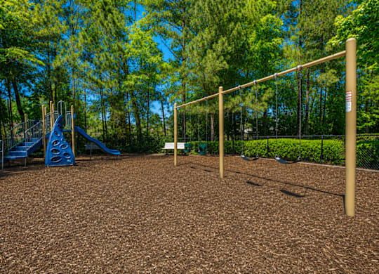 A playground with a slide, swings, and a monkey bars.