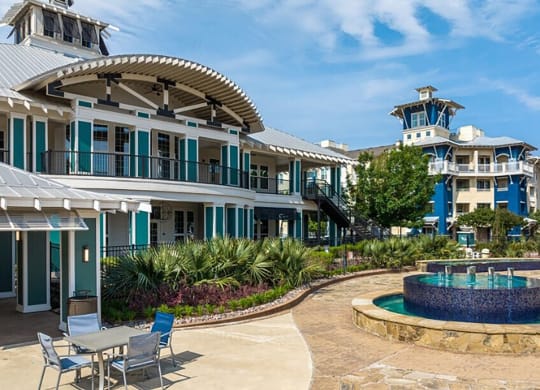 a fountain in front of a resort with tables and chairs
