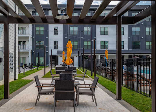 a patio with tables and chairs in front of an apartment building