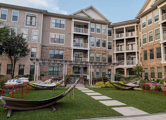 A large grassy area in front of apartment buildings with a boat-shaped seating area.