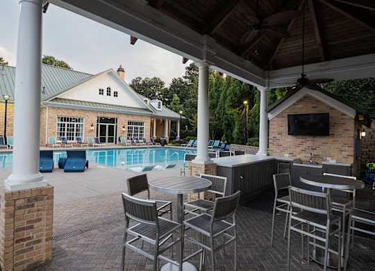 A patio with a table and chairs overlooking a pool.