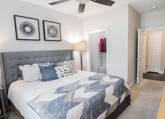 Dog-Friendly Luxury Apartments in Atlanta, GA - The Eliza on Collier - Bedroom with Large Bed, Ceiling Fan, Wall Art, Lamp, and Oversized Closet.