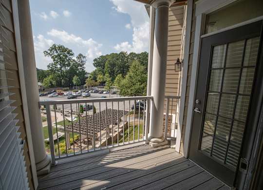 A balcony with a view of a parking lot and trees.