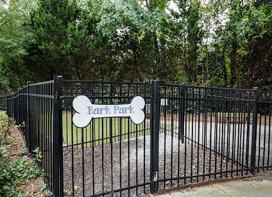 A black fence with a sign that says Bark Park.
