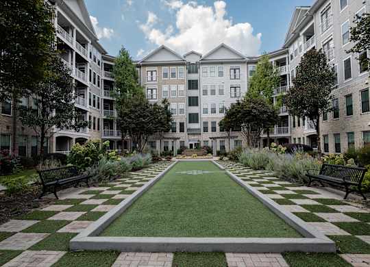 A courtyard with a green lawn and a checkerboard pattern of grass and concrete.