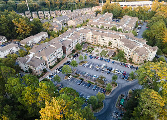 An aerial view of a parking lot surrounded by buildings and trees.