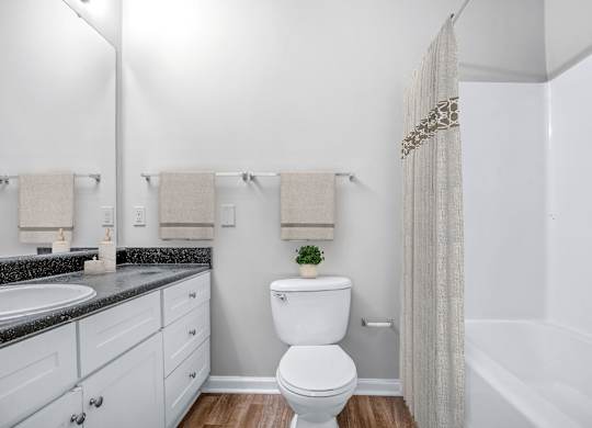 A white toilet in a bathroom with a white shower curtain.