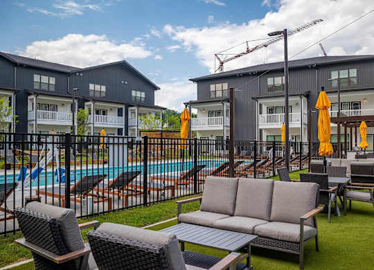 a pool with lounge chairs and tables in front of apartment buildings