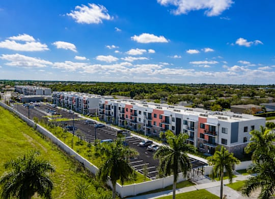 A row of colorful apartment buildings with a parking lot in front.