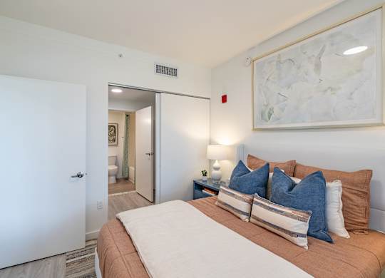 A bedroom with a large bed and a painting on the wall.
