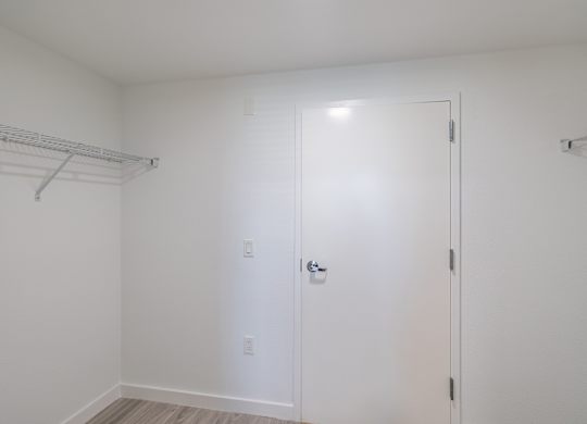 A white closet with a door and a shelf.