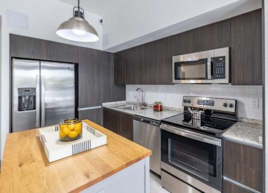 A modern kitchen with a wooden countertop and stainless steel appliances.