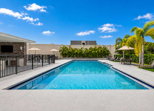 A large outdoor swimming pool surrounded by a black fence.