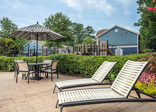A patio with a table, chairs, and an umbrella.