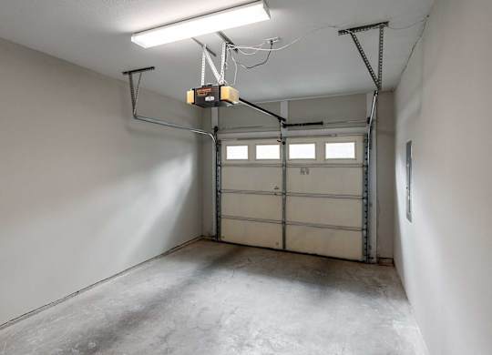 A garage with a white wall and a grey floor.