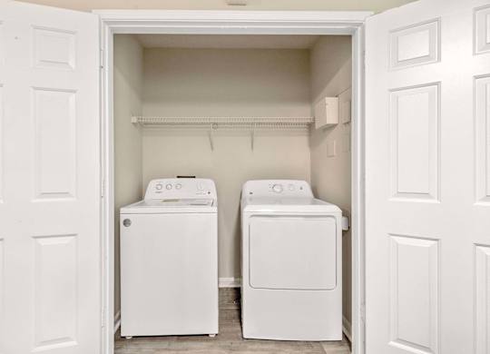 Two white washing machines in a small laundry room.
