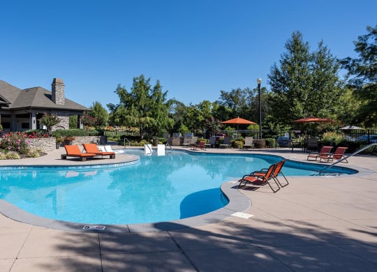 a swimming pool with chairs around it in front of a house
