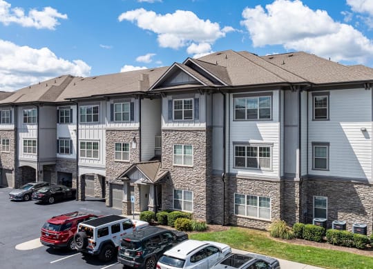 an apartment building with cars parked in a parking lot