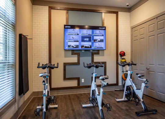 a home gym with exercise bikes and a tv on the wall