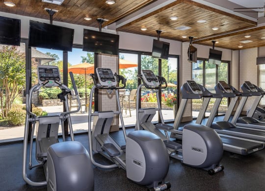 a gym with cardio equipment and windows