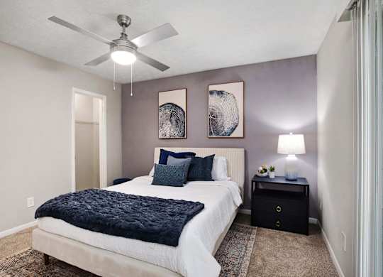 A bedroom with a bed, nightstand, and two wall art pieces.