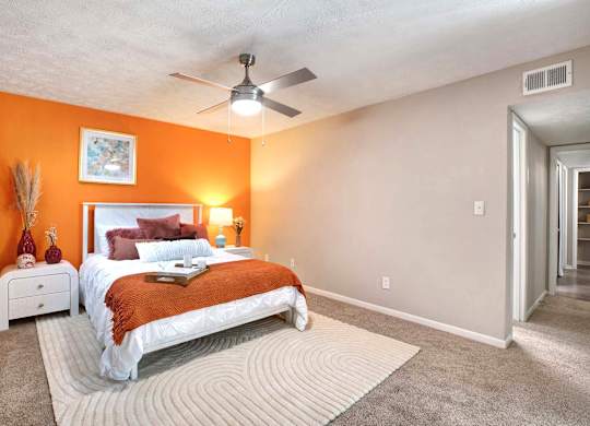 A bedroom with orange walls and a white bed.