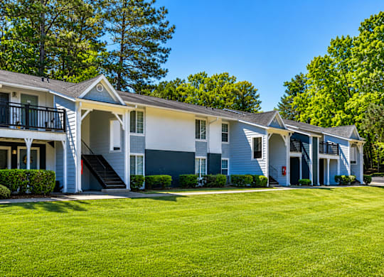 A row of townhouses with green lawns in front.