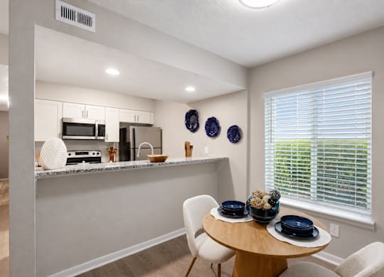 A kitchen with a table and chairs by a window.