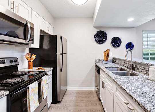 A kitchen with granite countertops and a black refrigerator.