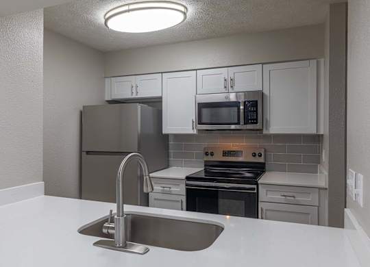 A kitchen with a sink, stove, and refrigerator.