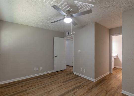 A room with a ceiling fan and wooden flooring.