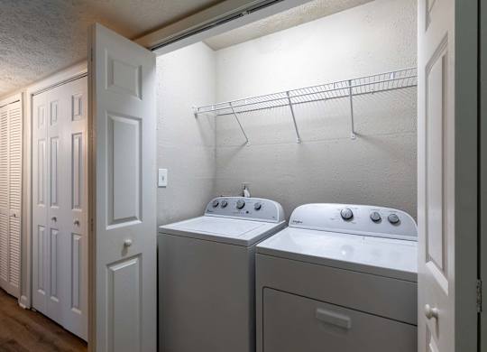A laundry room with two washing machines and a rack above them.