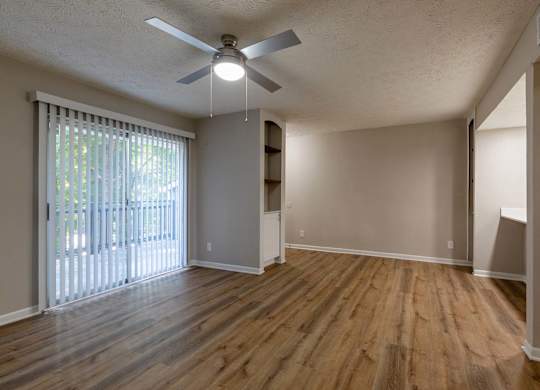 A room with a ceiling fan and wooden flooring.