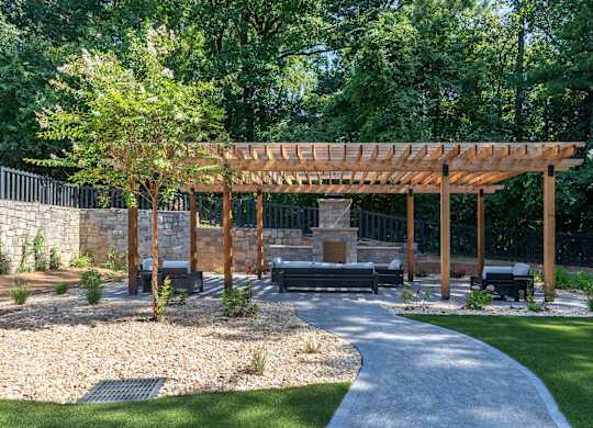 A wooden pergola is over a bench in a park.