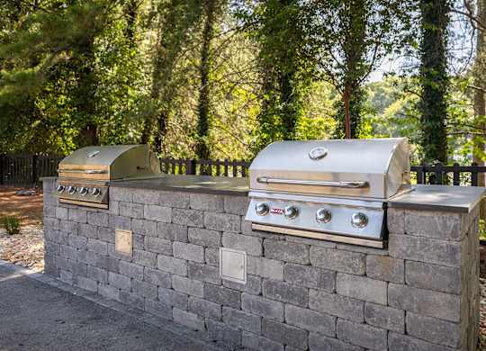 A silver grill is on top of a stone wall.