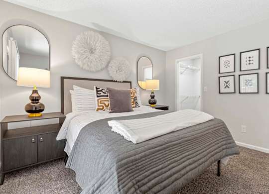 A bedroom with a large bed and two lamps.