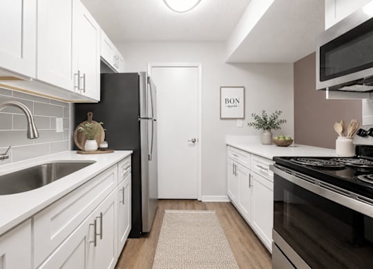 A kitchen with white cabinets and a black refrigerator.
