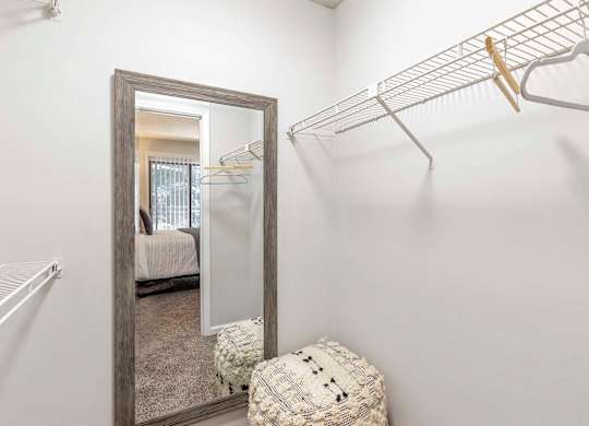 A white closet with a mirror and a shelf.