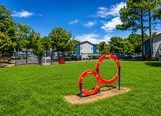 A red sculpture of two interlocking rings sits in a grassy field.